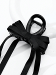 Detalhe do laço em cetim preto com quatro fitas compridas em mola de cabelo para menina