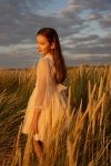 Menina com vestido de princesa bege Holly entre espigas ao fim da tarde
