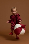 Menina bebé a brincar com bola de Natal vestida com vestido de veludo bordeaux