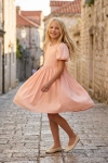 Vestido de cerimónia Sia cor-de-rosa – menina a rodar numa rua empedrada da cidade antiga