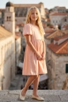 Vestido de cerimónia Sia cor-de-rosa – silhueta completa com a torre da cidade antiga ao fundo