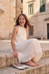 Vestido de cerimónia Rozalia branco plissado – exterior, menina sentada em escadas de pedra