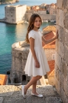 Vestido de cerimónia Rumi branco com mangas tulipa – exterior, junto a um muro de pedra