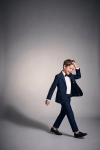Fato de cerimónia Sam azul-marinho com laço – menino em movimento, blazer aberto, silhueta completa