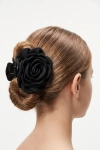 Pinça de cabelo preta com flor de tecido presa num carrapito baixo – vista de trás